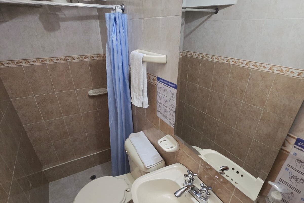 Un baño pequeño con inodoro, lavamanos y ducha.
