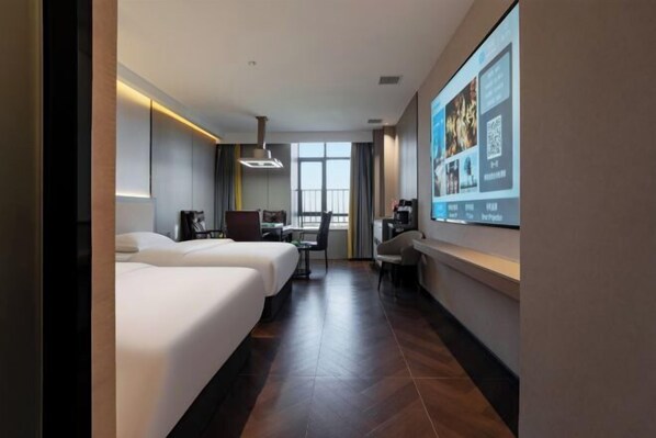 Une chambre d’hôtel avec deux lits, un bureau, une chaise, un grand écran et une fenêtre.