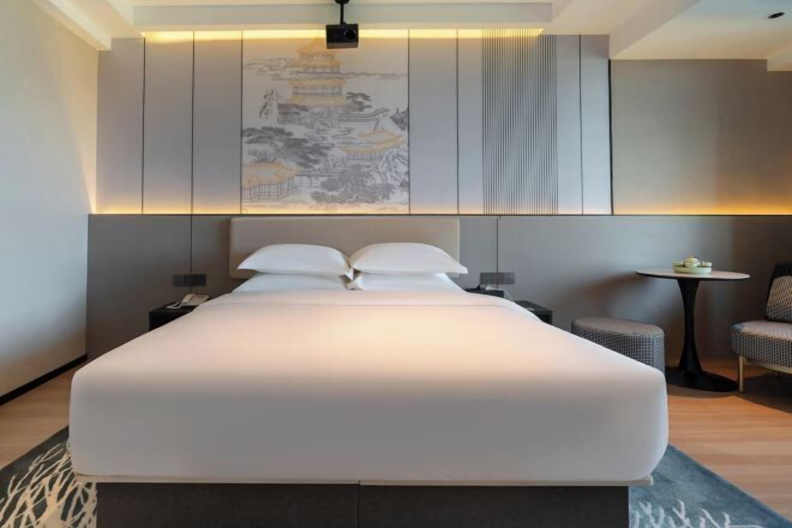 Een moderne hotelkamer met een groot bed, een kleine tafel en een stoel.