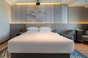 Una habitación de hotel moderna con una cama grande, una mesita y una silla.
