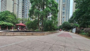 Un sendero pavimentado con un camino rojo, rodeado de árboles y un pequeño pabellón rojo.