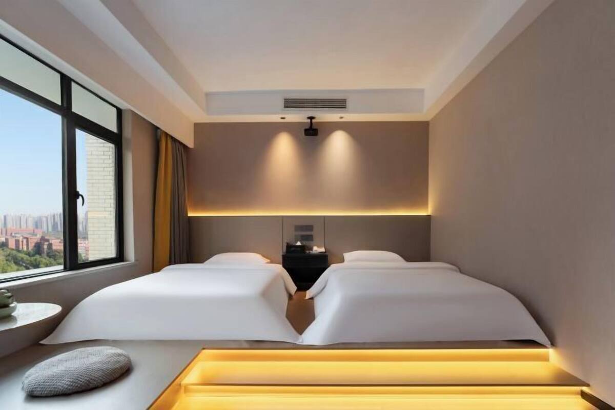 Quarto de hotel com duas camas, vista da cidade e design moderno.