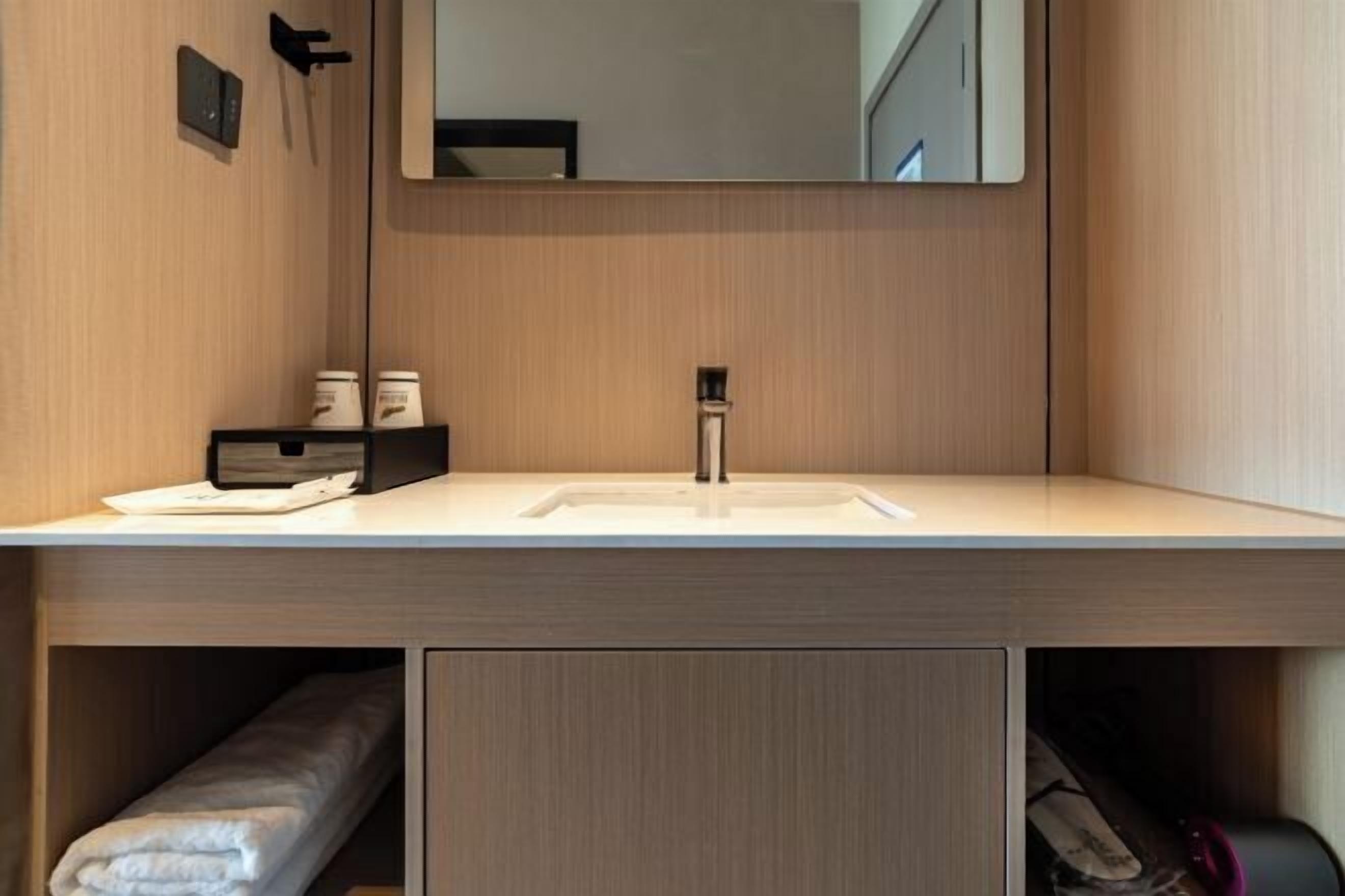 Un baño moderno con un espejo grande, un lavabo y un perchero para toallas.