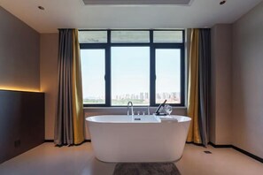 Ein modernes Badezimmer mit freistehender Badewanne, großen Fenstern und Blick auf die Stadtlandschaft.