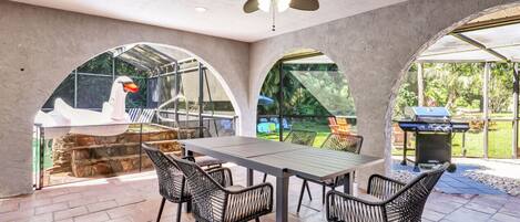 An outdoor patio with a table and chairs, a ceiling fan, and a barbecue grill.