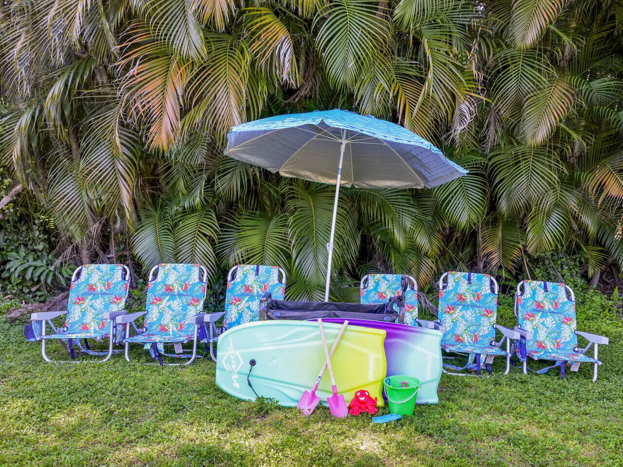 A row of beach chairs with a colorful umbrella and a surfboard in the center.