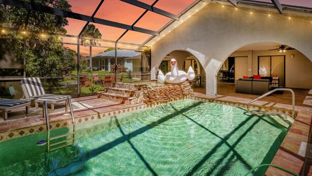 Una piscina interior amb sostre de vidre, una estàtua de cigne i vista del paisatge circumdant.