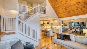A spacious loft with a wooden ceiling, a staircase, a kitchen, and a living area with a sofa and chairs. - Breathtaking Views-Ping Pong-Video Games- Hot Tub (Blue Ridge)