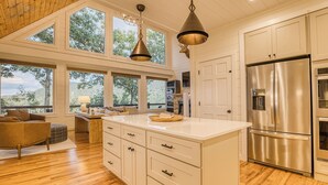 A modern kitchen with a large island, stainless steel appliances, and a view of the outdoors through large windows. - Breathtaking Views-Ping Pong-Video Games- Hot Tub (Blue Ridge)