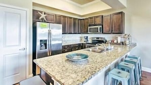 A modern kitchen with dark wood cabinets, stainless steel appliances, and a granite countertop. - D's by the Sea - 3 BR condo steps from the beach (Miramar Beach)