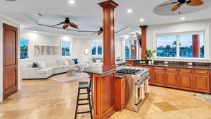 A spacious kitchen with a central island, wooden cabinets, and a large window offering a view of the outdoors.