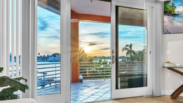 A room with a large sliding glass door leading to a balcony with a city view.