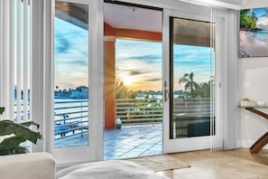 A room with a large sliding glass door leading to a balcony with a city view.