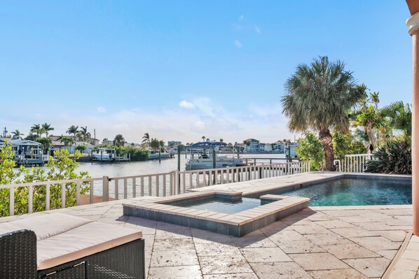 A pool area with a view of the marina, including boats and palm trees.