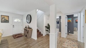 A spacious hallway with wooden flooring, a staircase, and a door leading to a bathroom. - Cleopatra's Sunset in Ocala (Ocala)