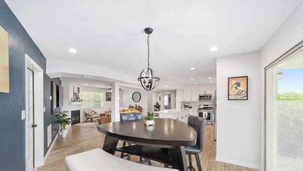 A modern kitchen with white cabinets, a central island, and a dining area with a round table and bench. - Cleopatra's Sunset in Ocala (Ocala)