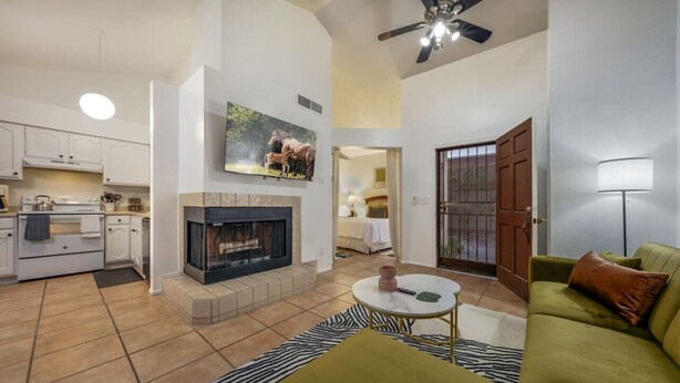 A living room with a fireplace, a green sofa, and a television mounted on the wall.