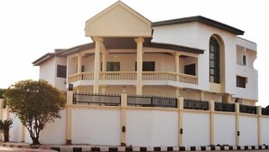 A two-story building with a balcony on the second floor, a large arched window on the upper level, and a flat roof.