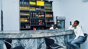 A bar area with a marble countertop and black chairs. There are shelves with various bottles and a sign that reads "RESTPOINT".