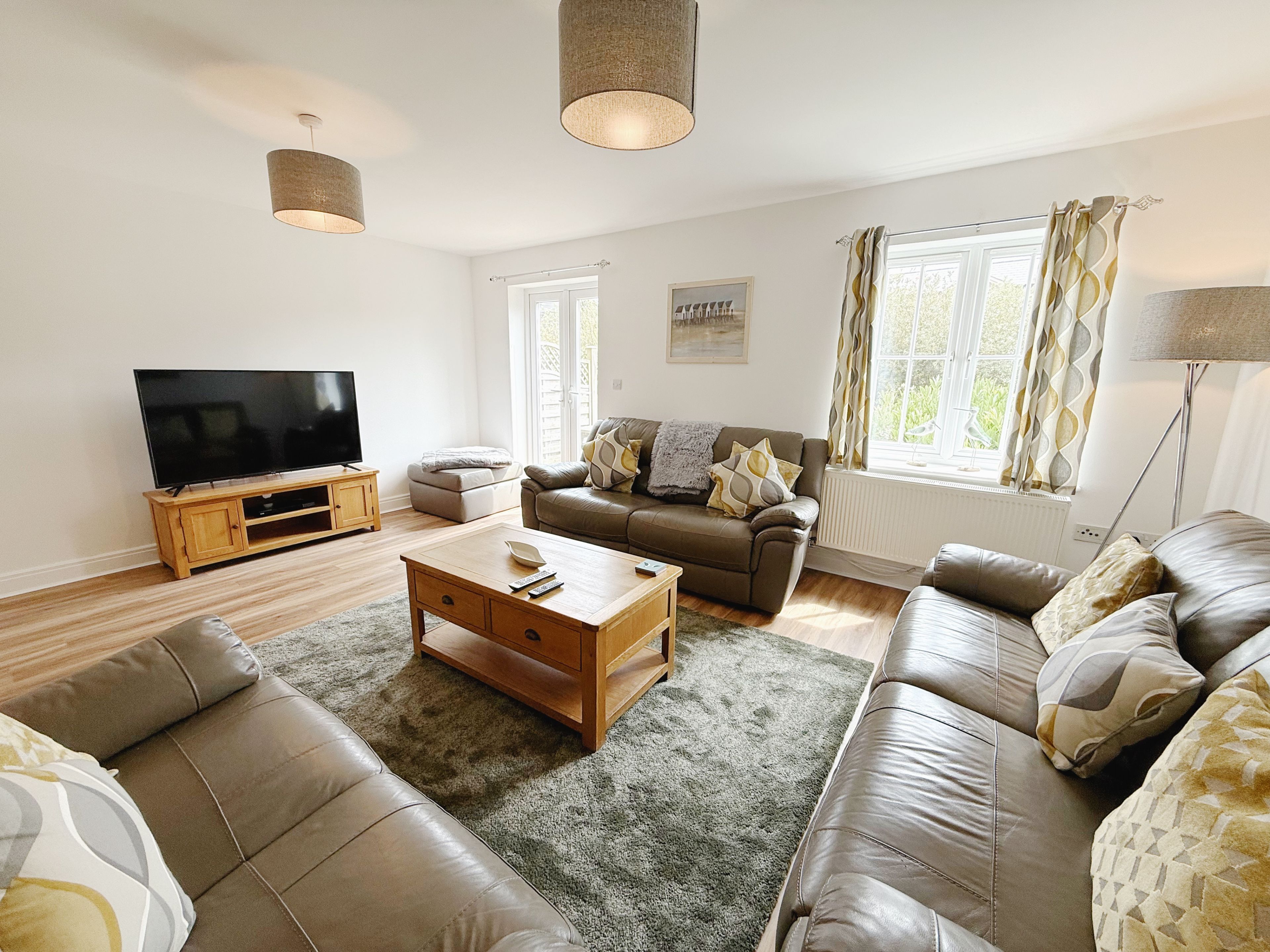 A living room with a flat-screen TV, leather sofas, a coffee table, and a lamp.