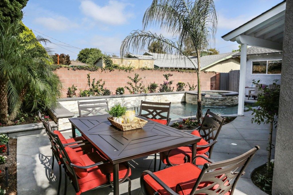 An outdoor patio with a table and chairs, a small pool, and a brick wall with vegetation.