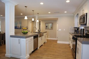 A modern kitchen with white cabinetry, stainless steel appliances, and pendant lighting. - Fantastic 6 bedroom 4 bath Pool Home (Anaheim)