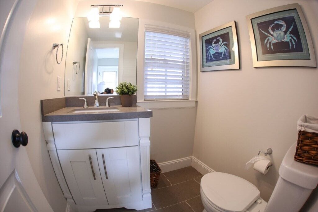 Ein Badezimmer mit weißem Waschtisch, Toilette und zwei gerahmten Bildern an der Wand.