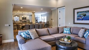 A modern living room with a sectional sofa, ottoman, and a dining area in the background. - Fantastic 6 bedroom 4 bath Pool Home (Anaheim)