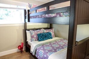 A bunk bed with floral bedding, a red umbrella, and a window with a view.