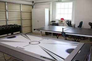 A ping pong table, a foosball table, and a window with natural light.