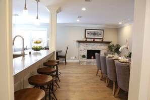 A kitchen with a bar area, a fireplace, and a dining table with chairs. - Fantastic 6 bedroom 4 bath Pool Home (Anaheim)