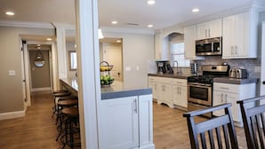 A modern kitchen with white cabinetry, a central island with bar stools, a built-in oven, and a microwave. - Fantastic 6 bedroom 4 bath Pool Home (Anaheim)