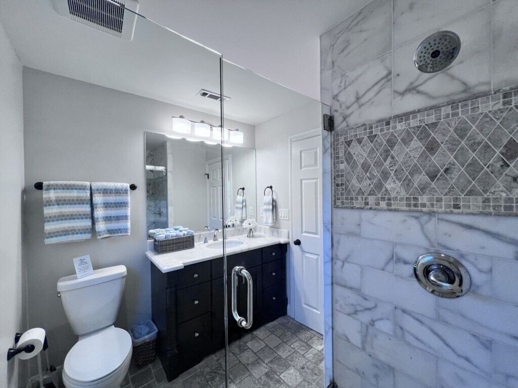 Un baño con inodoro, lavamanos y zona de ducha.