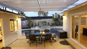 Une terrasse avec une piscine, des sièges d’extérieur et un ventilateur de plafond.