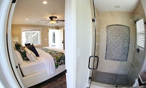 A bedroom with a bed, a ceiling fan, and a bathroom with a shower.