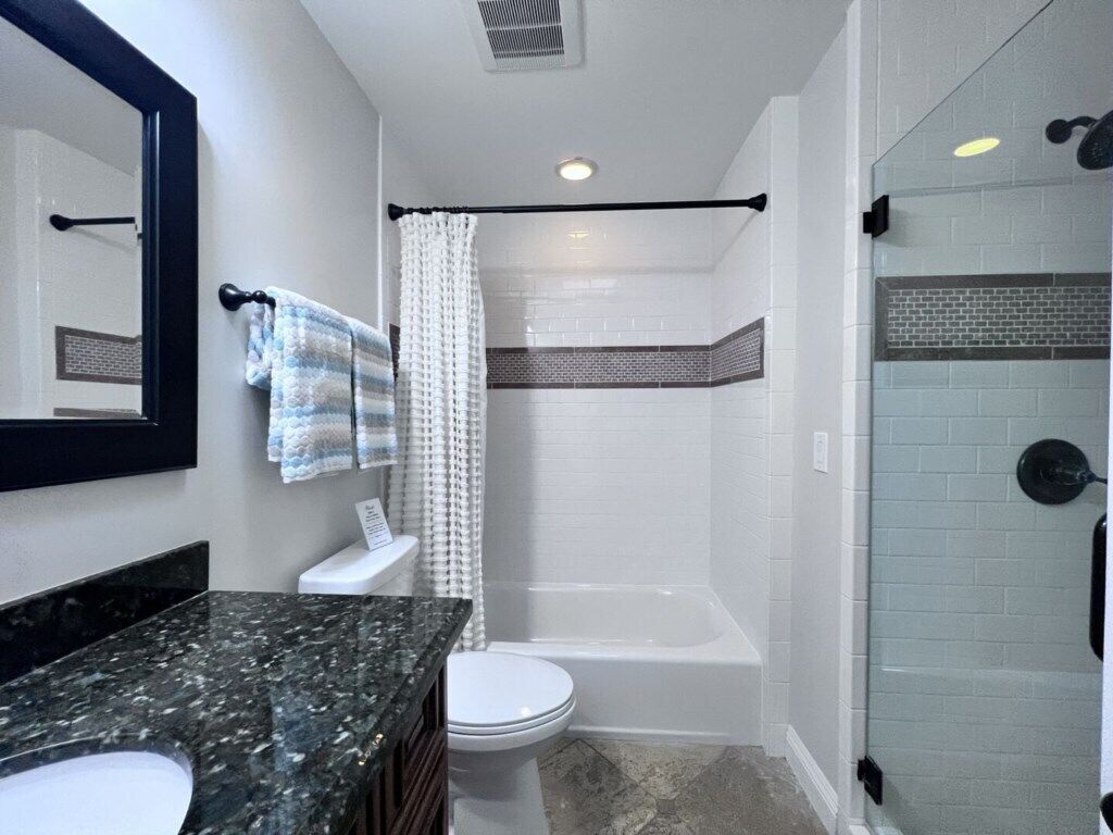 A bathroom with a shower, toilet, and a vanity with a sink.