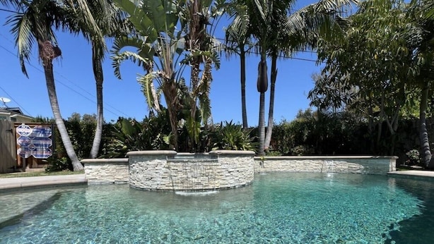 Une piscine aux eaux cristallines, entourée de murs de pierre et de palmiers.