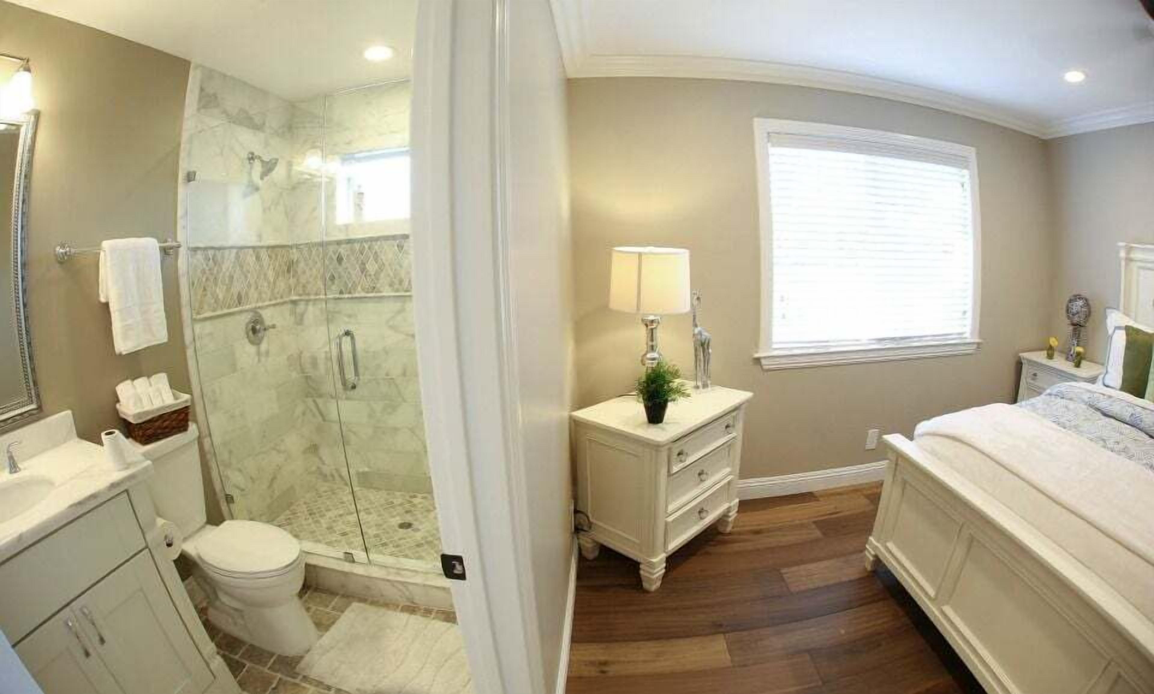 Une salle de bain avec une douche à parois de verre, des toilettes, un lavabo et un meuble-lavabo avec un miroir.