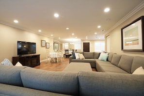 A living room with a sofa, TV, dining table, and chairs.