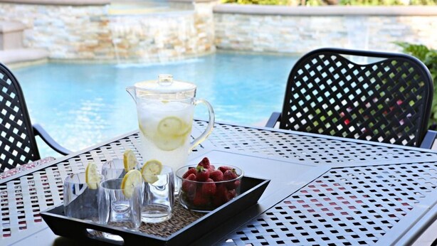 A table with a pitcher of lemonade, glasses, and a bowl of strawberries by a pool. - Upscale 6 Bed, 5 Ba, New Pool W/jacuzzi, 1/2 Mile Walk to Disney (Anaheim)