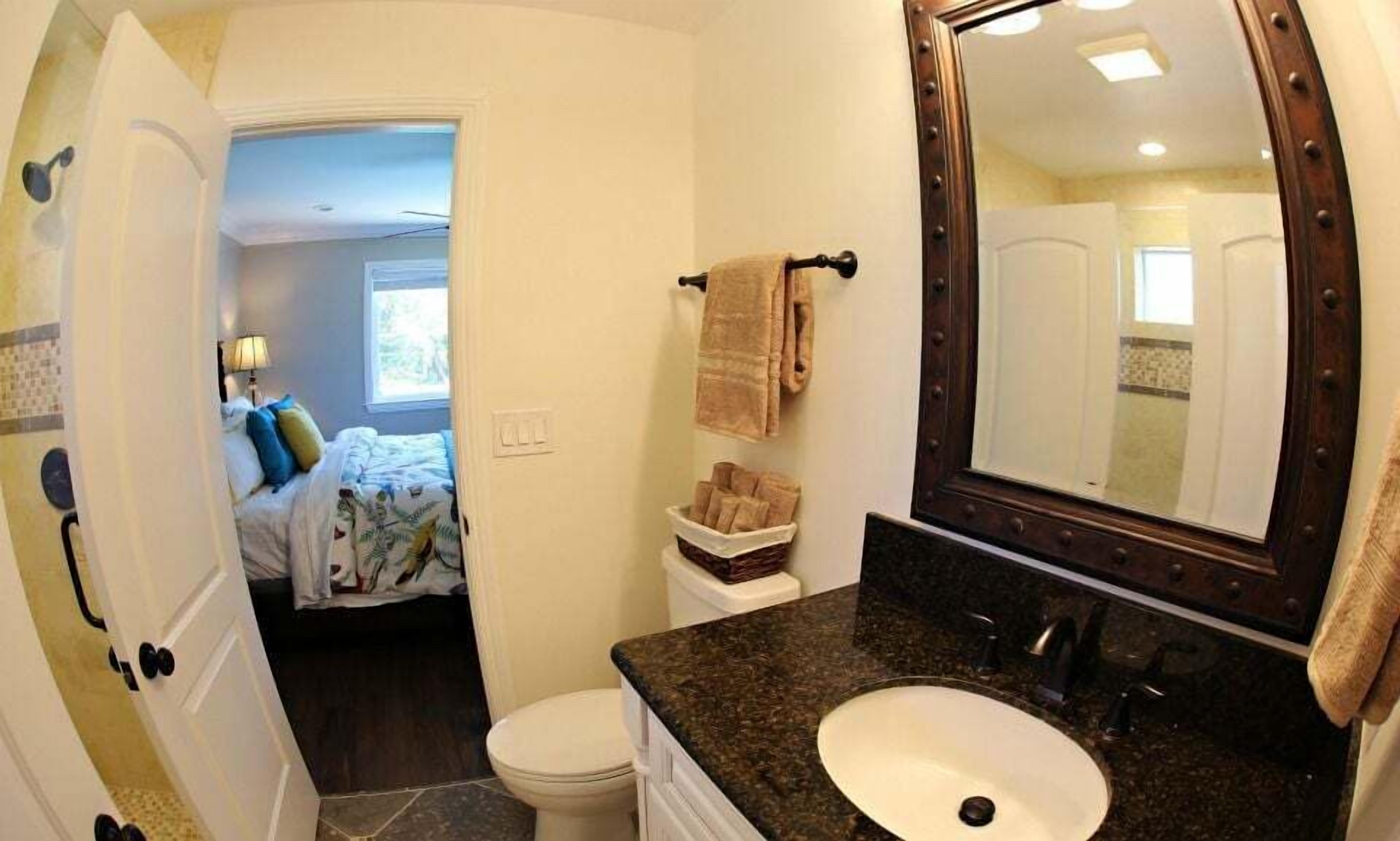 A bathroom with a large mirror, a sink, a toilet, and a towel rack.