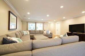 Un saló amb un sofà modular, una televisió de pantalla plana i llums d'encastrament al sostre.