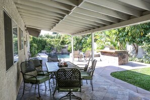Un patio cubierto con piscina, mobiliario exterior y abundante vegetación.
