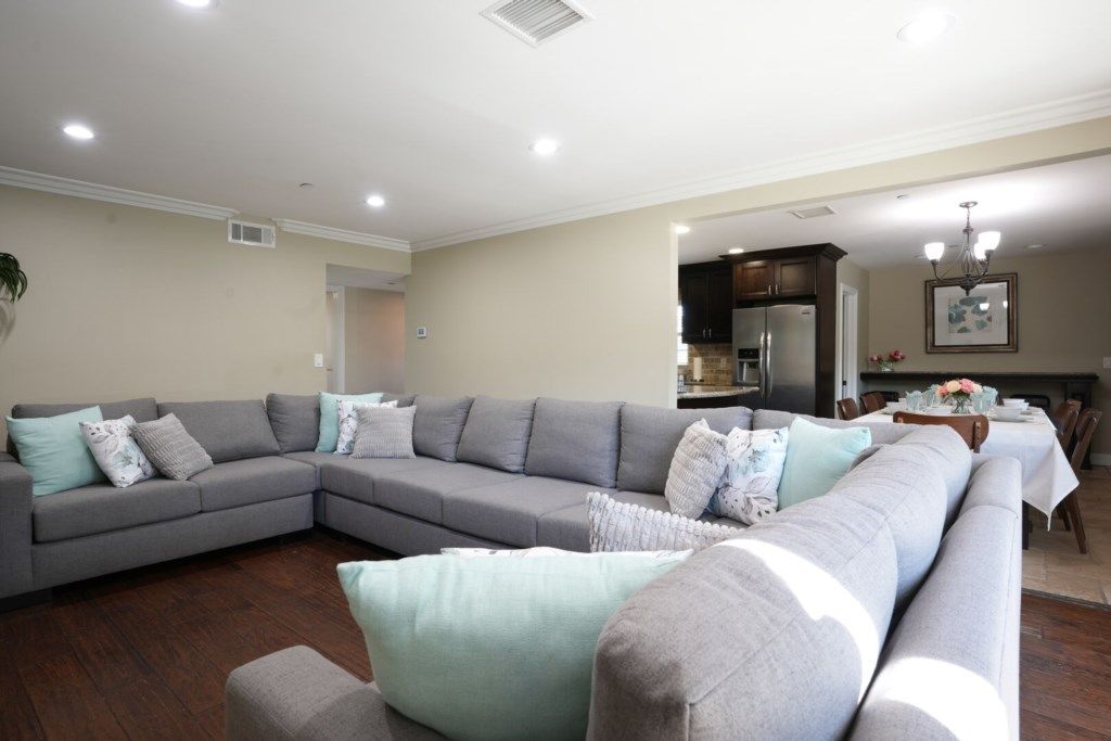 A modern living room with a sectional sofa, a dining table, and a kitchen area.