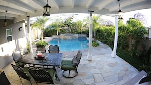 A covered patio with a pool, outdoor furniture, and stone flooring. - Highly Upgraded, 5 Bed, 4.5 ba, New Pool W/jacuzzi, 1/2 Mile Walk to Disney (Anaheim)