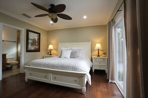 A bedroom with a bed, bedside tables, a ceiling fan, and a window with curtains.