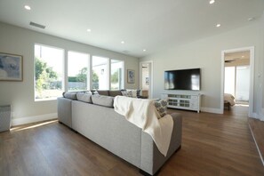 A spacious living room with a large sofa, a TV, and a fireplace. - 4 bedroom, 2 bathrooms (Orange)