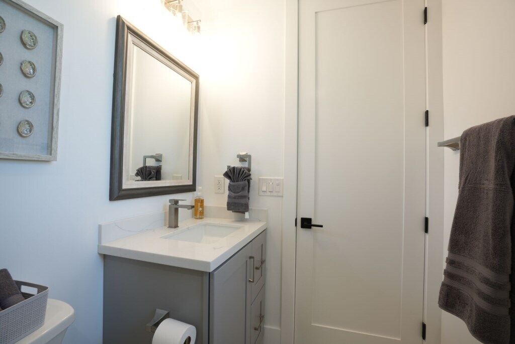 Un baño con lavabo blanco, espejo y barra para toallas.