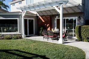 A covered patio with a table and chairs, a brick wall, and a glass door leading to a garage.