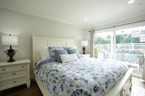 A bedroom with a bed, nightstands, and a view of the outside.